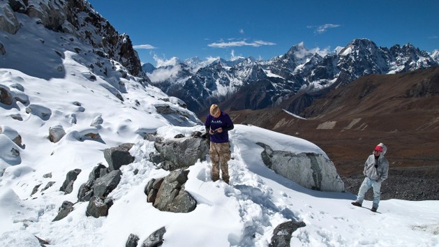 Trekkers moving across snow and rocks on Cho La Pass in Nepal's Everest region